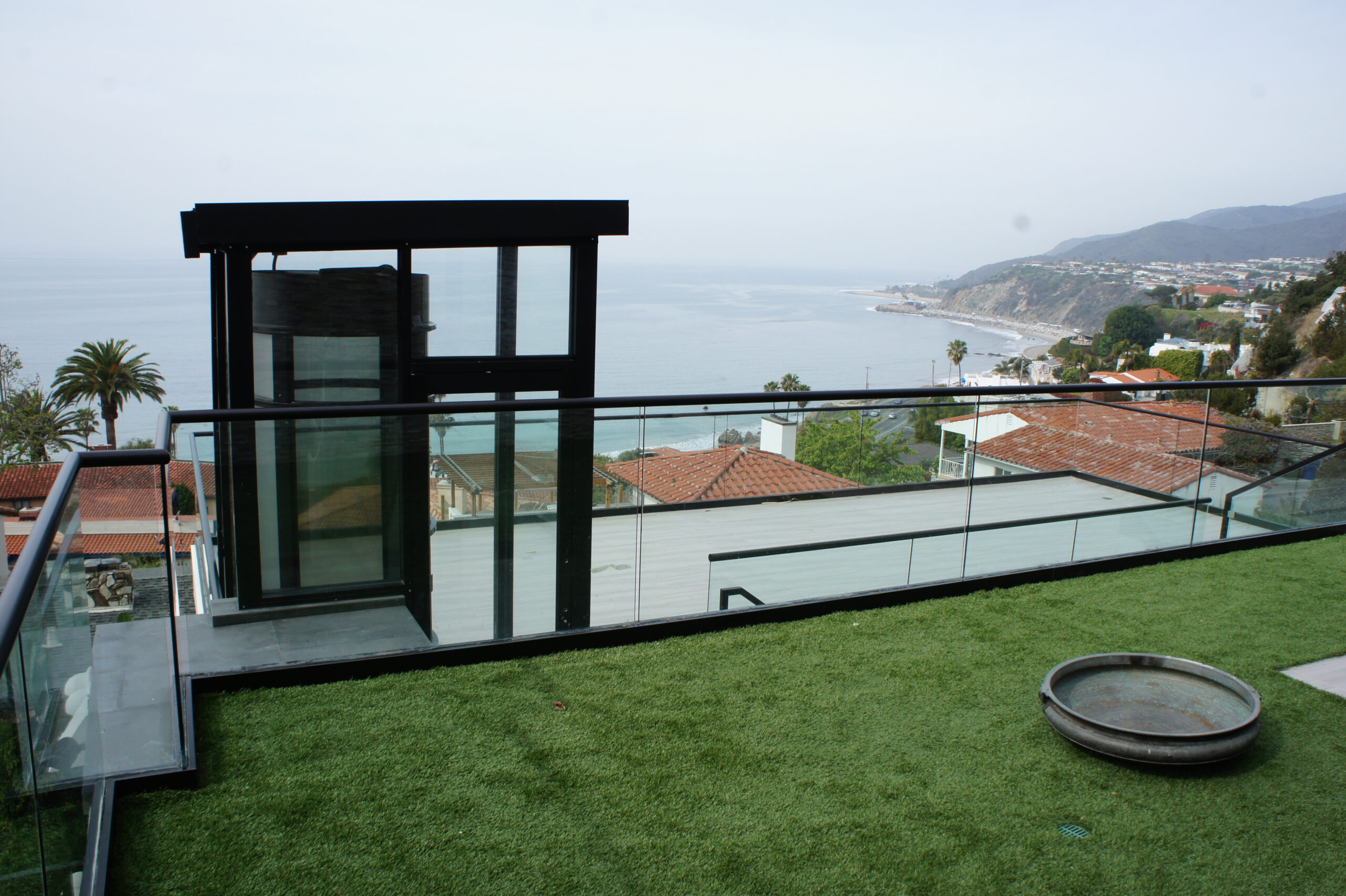 pve elevator installed in a glass enclosure on an outdoor stone deck overlooking the ocean